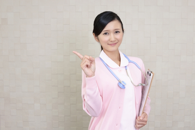 指を指すピンクの制服の医師
