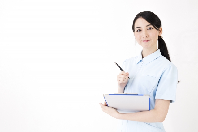 白い背景でメモを取る女性看護師
