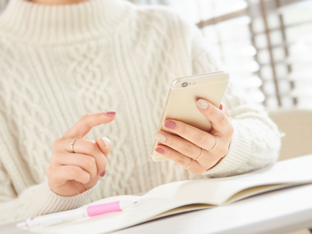 スマートフォンを持つ白いセーターの女性